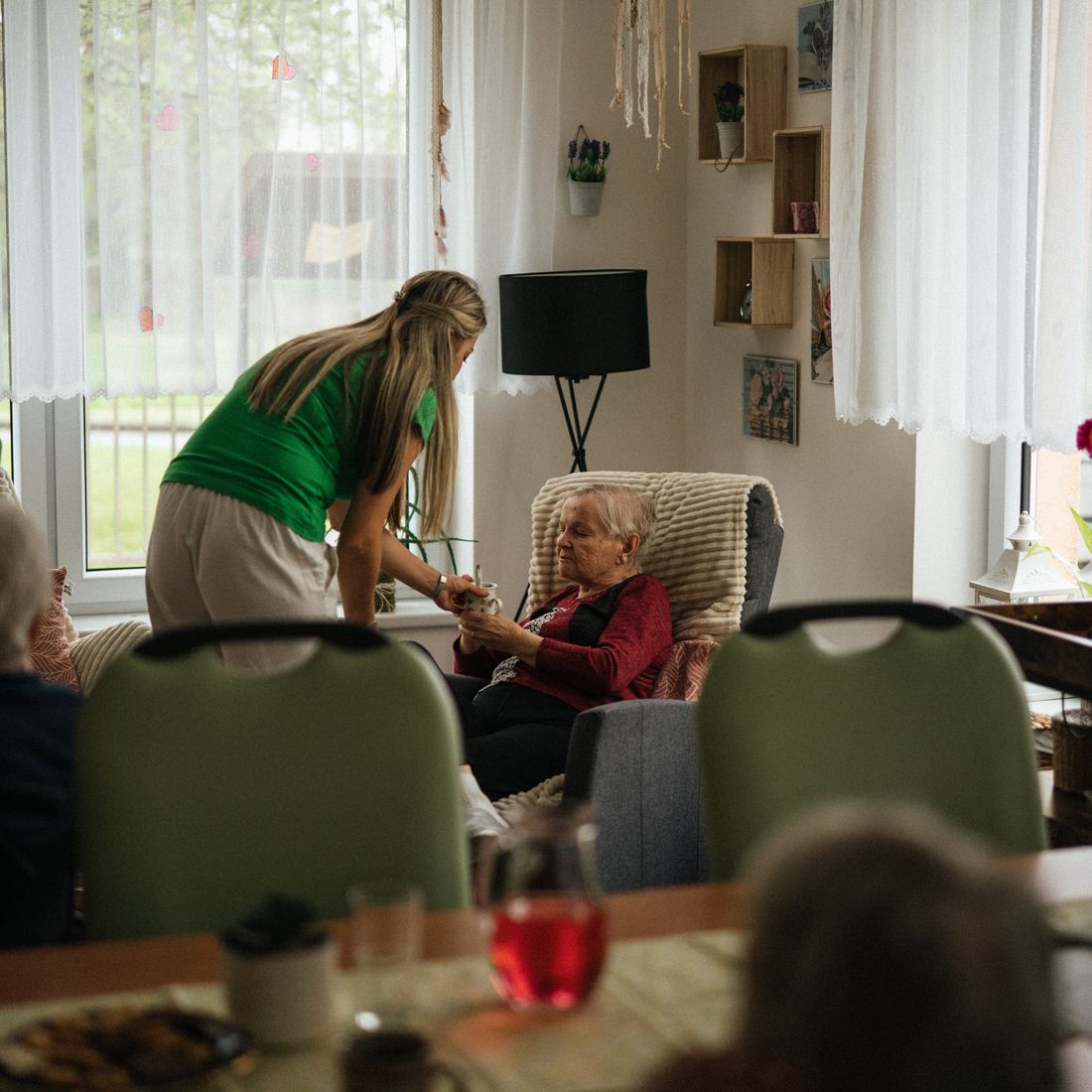 A caregiver assisting a resident in a care-home common room
