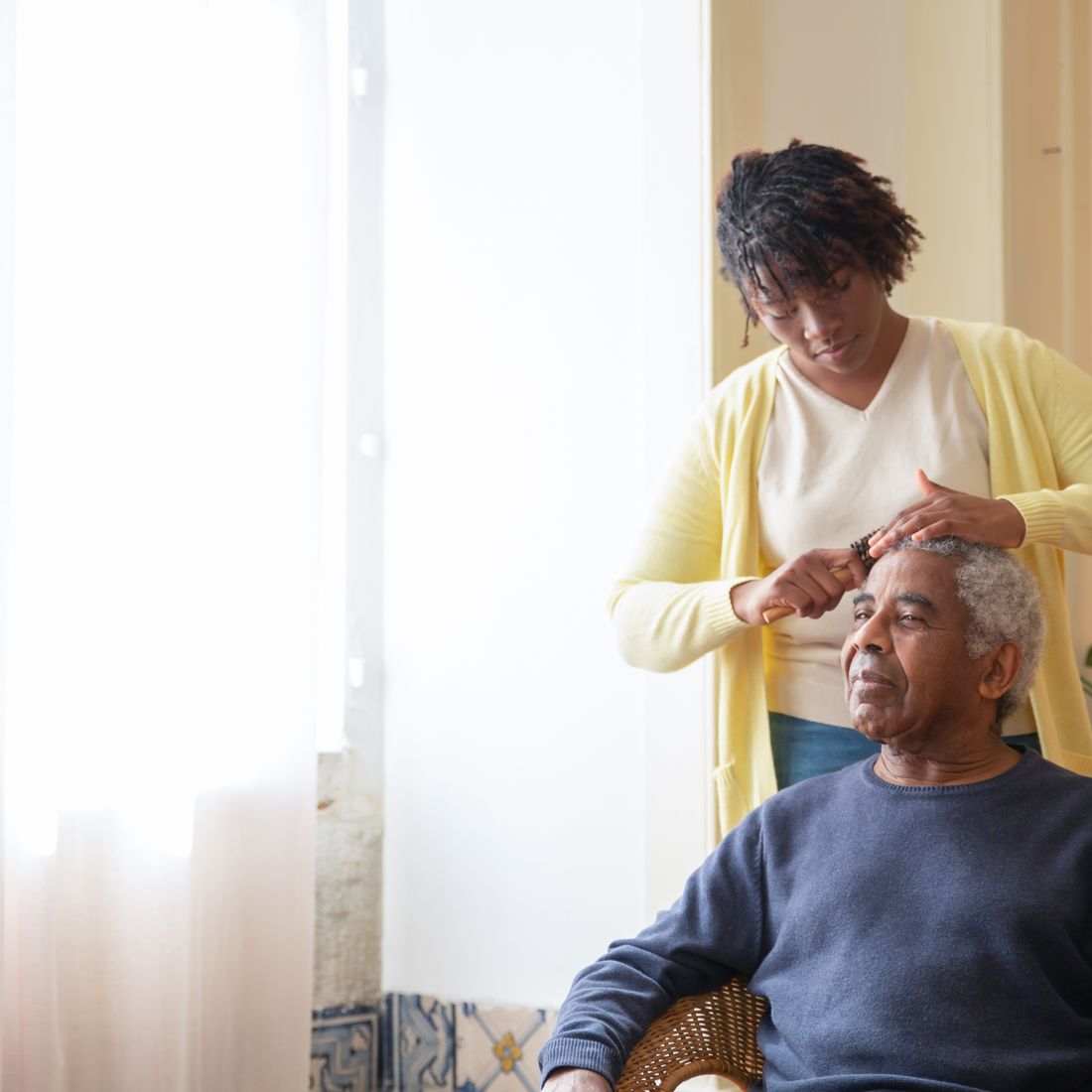 A caregiver helping a senior with grooming by a sunny window